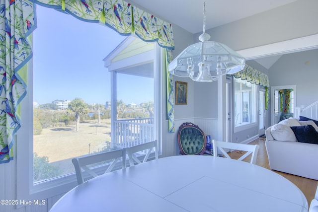 dining room with lofted ceiling, wood finished floors, and wainscoting