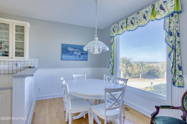 dining area featuring a wainscoted wall, a notable chandelier, and light wood-style floors