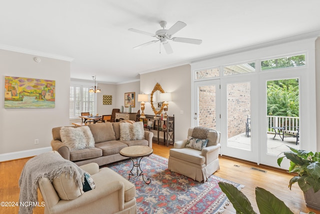 living room with light wood-type flooring, ornamental molding, and ceiling fan with notable chandelier