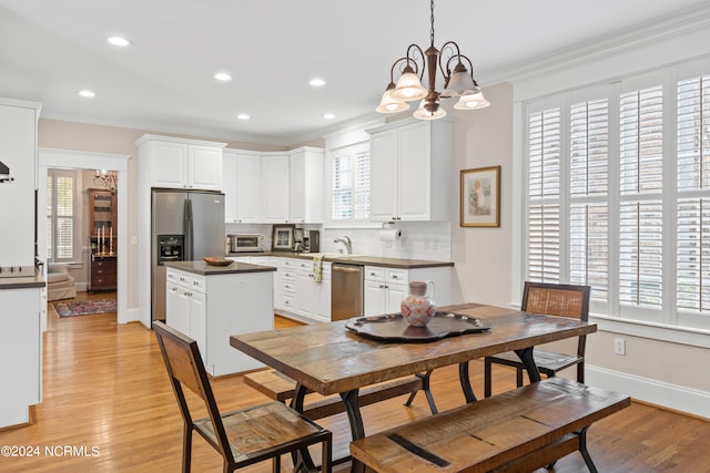 kitchen with tasteful backsplash, light hardwood / wood-style floors, hanging light fixtures, stainless steel appliances, and white cabinets