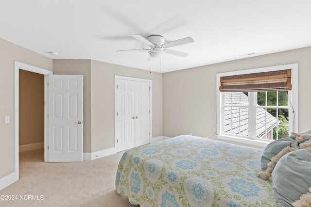 bedroom featuring light colored carpet, ceiling fan, and a closet