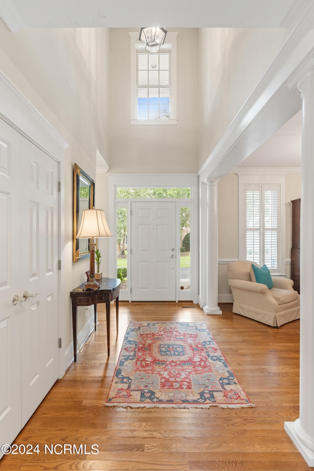 foyer featuring decorative columns, plenty of natural light, and light hardwood / wood-style floors