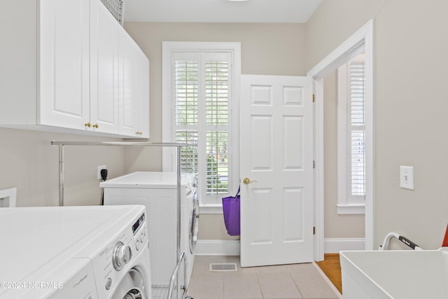 laundry room with cabinets, light tile patterned floors, and washer and clothes dryer