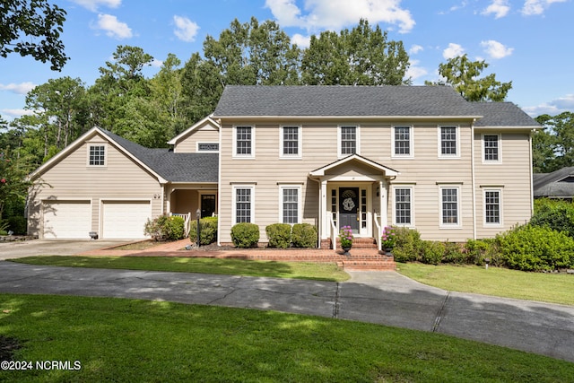 colonial home featuring a garage and a front lawn