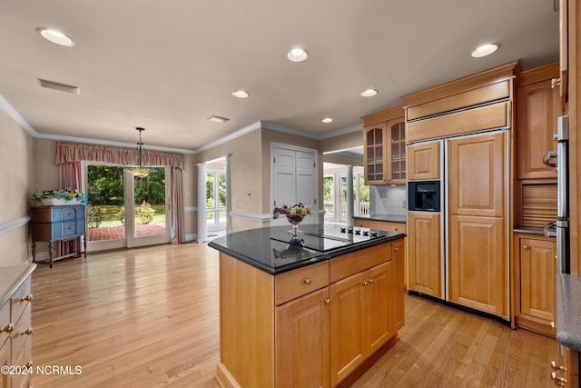 kitchen with paneled built in fridge, ornamental molding, light hardwood / wood-style floors, decorative light fixtures, and a center island