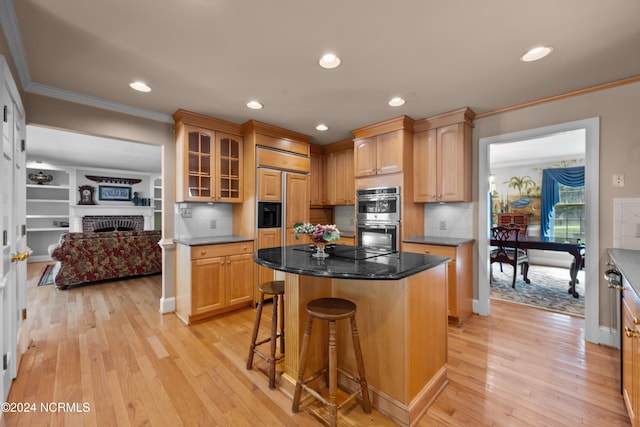 kitchen with a fireplace, stainless steel double oven, light hardwood / wood-style floors, tasteful backsplash, and a kitchen island