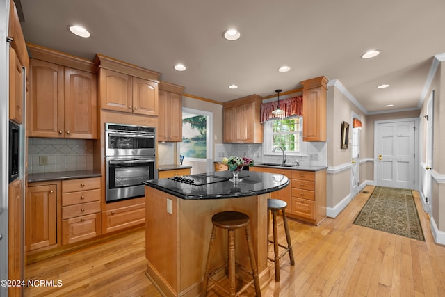 kitchen featuring backsplash, light wood-type flooring, stainless steel double oven, a kitchen island, and pendant lighting