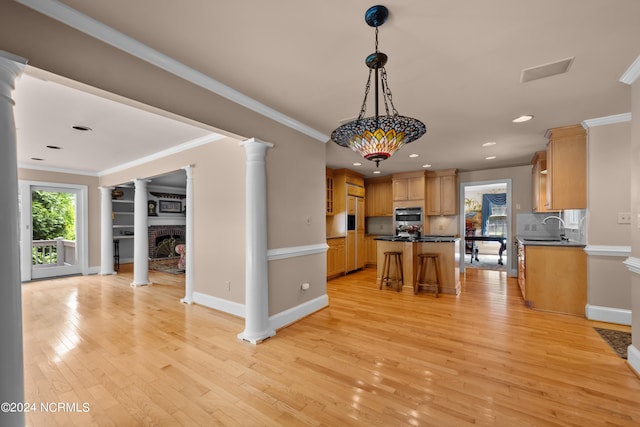 kitchen featuring light wood-type flooring, tasteful backsplash, sink, a fireplace, and a center island