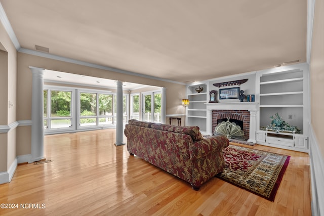 living room featuring light hardwood / wood-style flooring, ornamental molding, decorative columns, and a brick fireplace