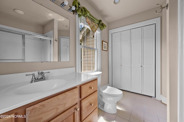 bathroom with tile patterned flooring, toilet, a healthy amount of sunlight, and vanity