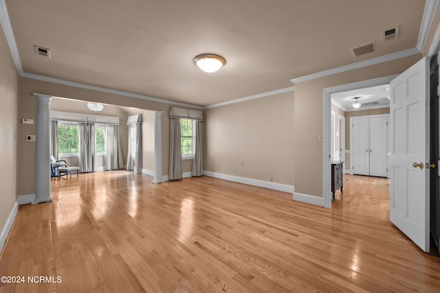 interior space with light wood-type flooring, crown molding, and ornate columns