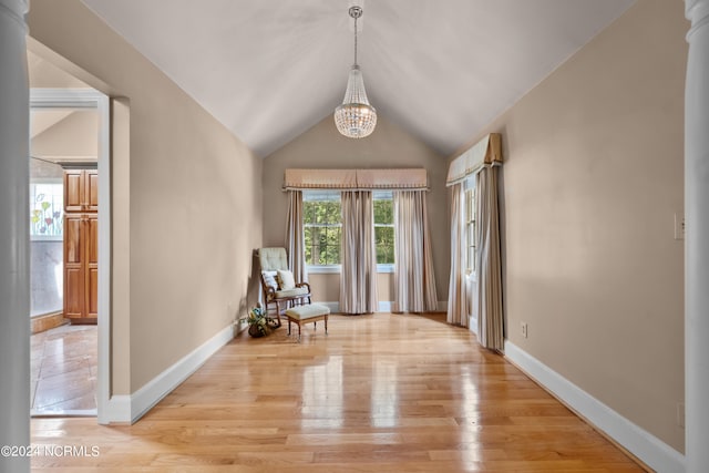 interior space with vaulted ceiling, an inviting chandelier, and light wood-type flooring