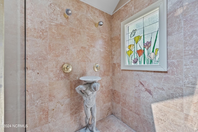 bathroom with a wealth of natural light, tiled shower, and lofted ceiling