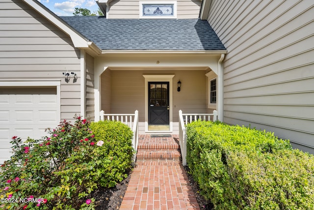 view of exterior entry with a garage and covered porch