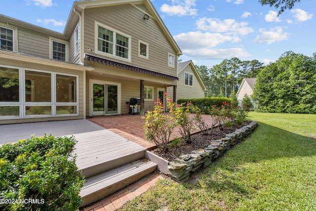 back of property with a yard and a wooden deck