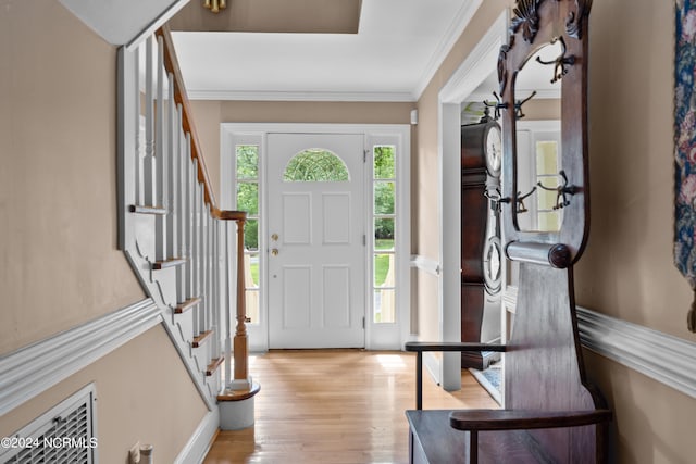 foyer entrance with light hardwood / wood-style floors and ornamental molding