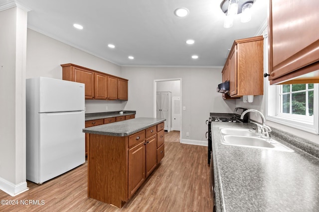 kitchen with dark countertops, brown cabinetry, freestanding refrigerator, a kitchen island, and light wood-type flooring