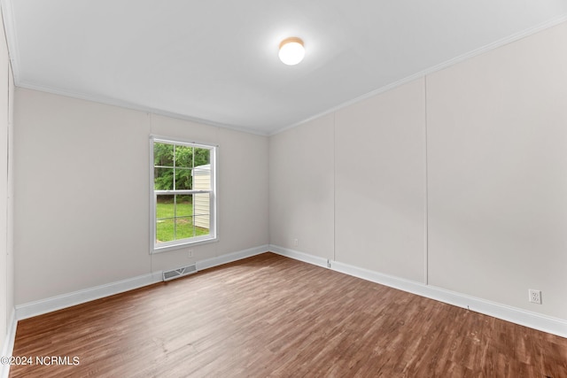 empty room with visible vents, crown molding, baseboards, and wood finished floors