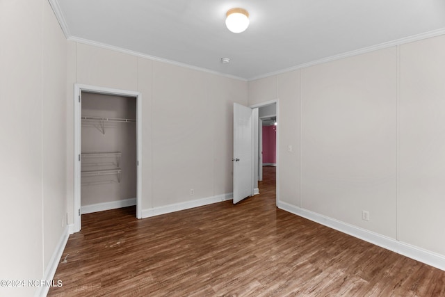 unfurnished bedroom with ornamental molding, a closet, dark wood finished floors, and a decorative wall