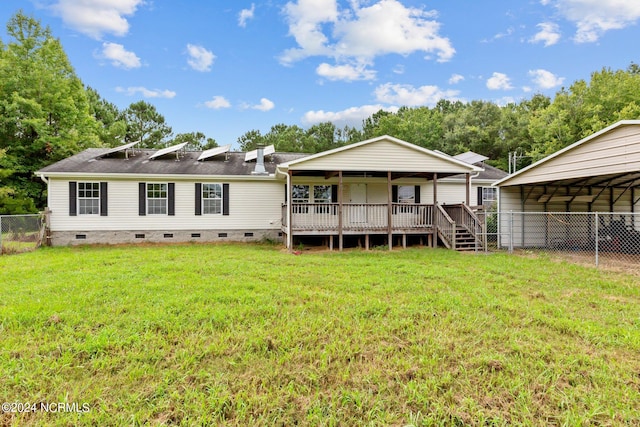 rear view of house featuring a deck, a lawn, and a carport