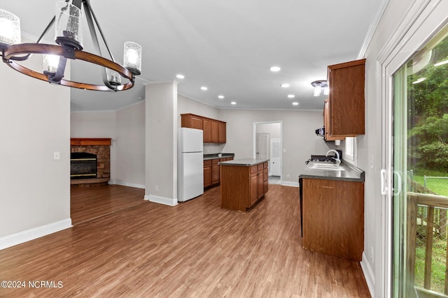 kitchen with a kitchen island, brown cabinets, wood finished floors, freestanding refrigerator, and a sink