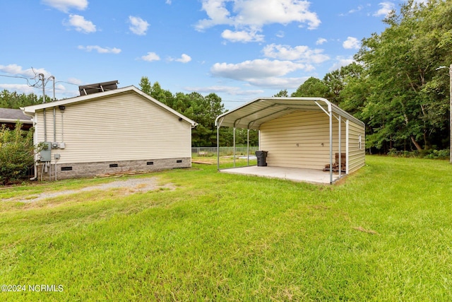 view of yard with driveway, fence, and a detached carport