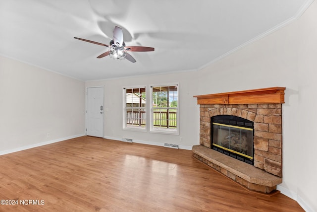 unfurnished living room with a stone fireplace, wood finished floors, visible vents, baseboards, and ornamental molding