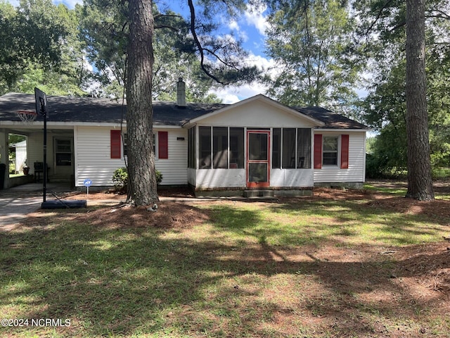 view of front of home featuring a sunroom, a front lawn, and a carport