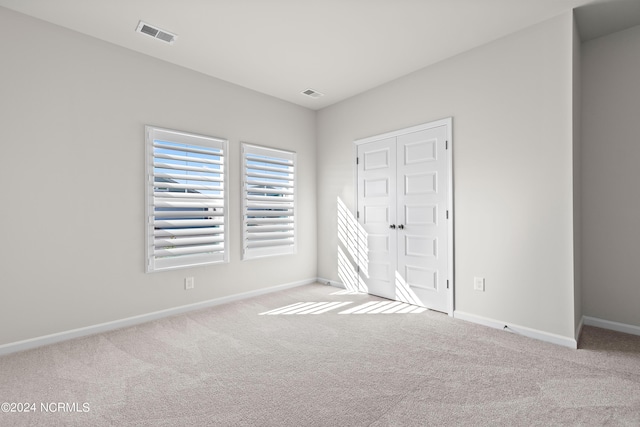 unfurnished bedroom featuring light carpet and a closet