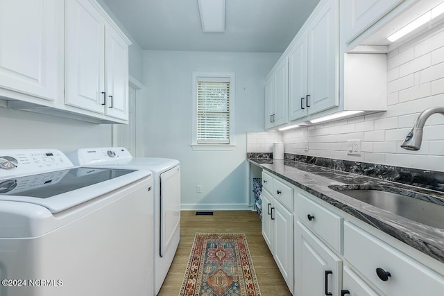 clothes washing area featuring washer and dryer, sink, cabinets, and dark hardwood / wood-style floors