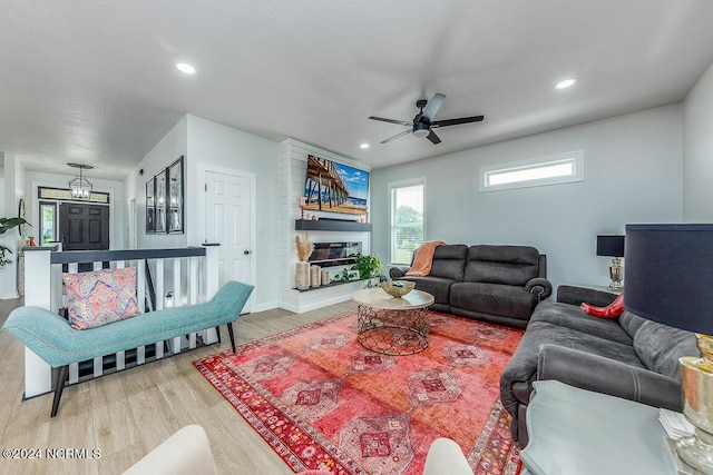 living room with wood-type flooring, ceiling fan, and a fireplace