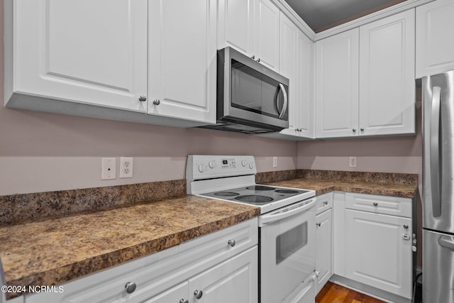 kitchen with appliances with stainless steel finishes, dark countertops, light wood-type flooring, and white cabinetry