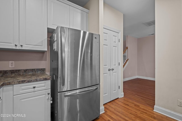 kitchen with light wood-style flooring, baseboards, white cabinets, freestanding refrigerator, and dark countertops