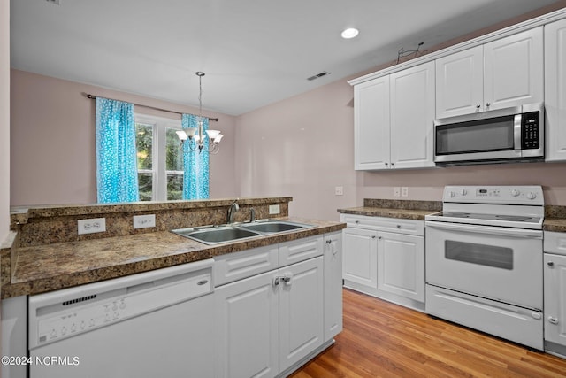 kitchen with dark countertops, white appliances, white cabinets, and a sink