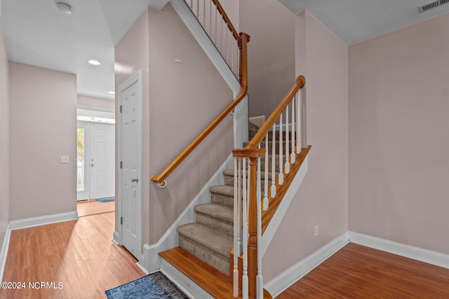 stairs featuring wood finished floors, visible vents, and baseboards