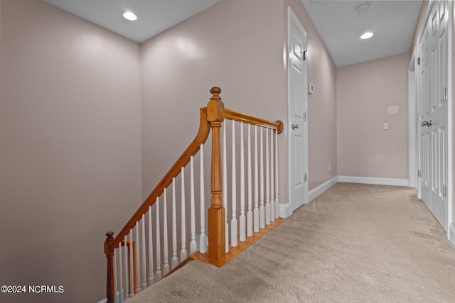 hallway featuring recessed lighting, baseboards, light carpet, and an upstairs landing