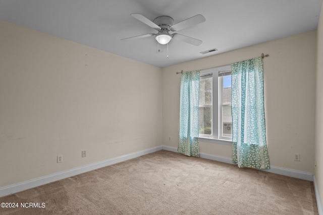 empty room featuring baseboards, visible vents, ceiling fan, and light colored carpet