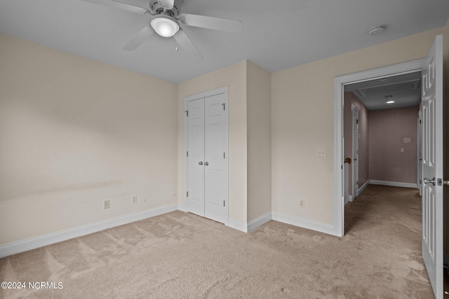 unfurnished bedroom featuring a ceiling fan, baseboards, a closet, and light colored carpet