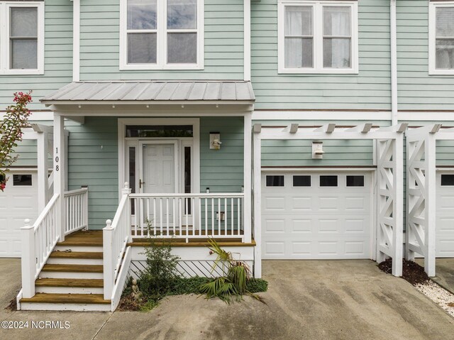 view of exterior entry featuring a porch and a garage