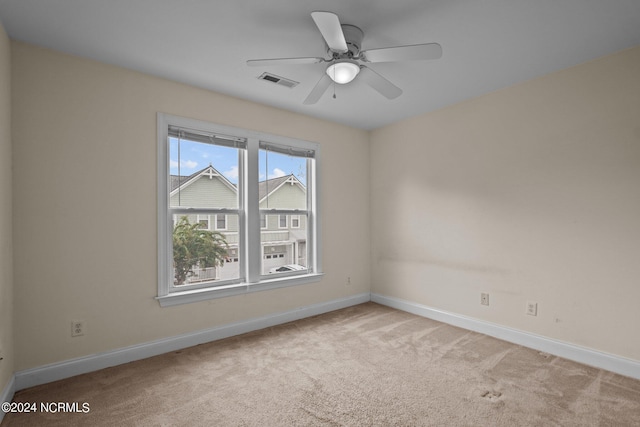 spare room with light carpet, a ceiling fan, visible vents, and baseboards