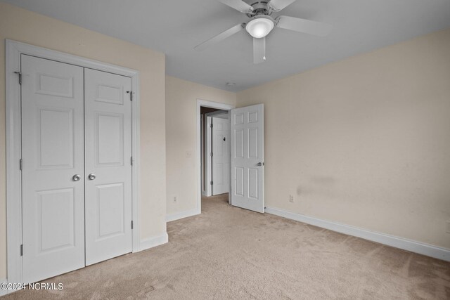 unfurnished bedroom with a ceiling fan, baseboards, a closet, and light colored carpet