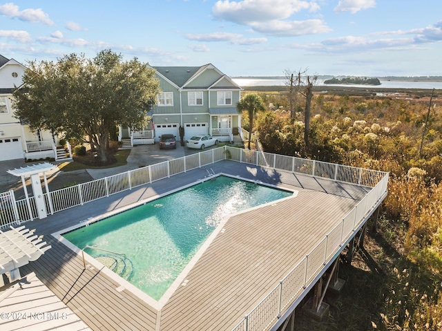 community pool featuring a water view, fence, and a pergola