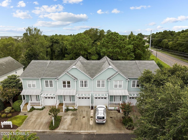 view of front of home featuring a garage, a standing seam roof, roof with shingles, and driveway