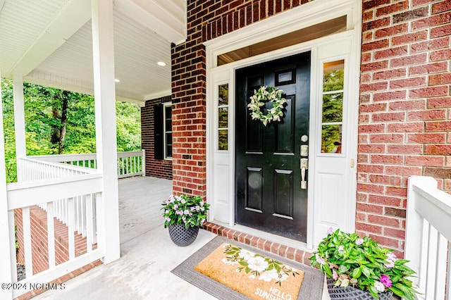 doorway to property featuring brick siding and a porch