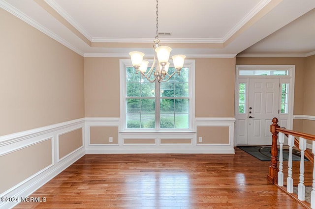 foyer featuring a decorative wall, an inviting chandelier, ornamental molding, wainscoting, and hardwood / wood-style flooring