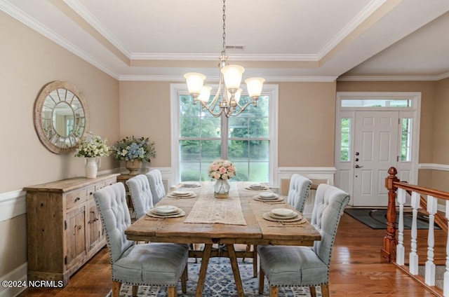 dining room with crown molding, a wainscoted wall, a notable chandelier, and wood finished floors