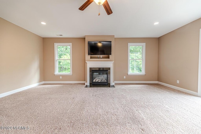 unfurnished living room featuring carpet, recessed lighting, baseboards, and a premium fireplace