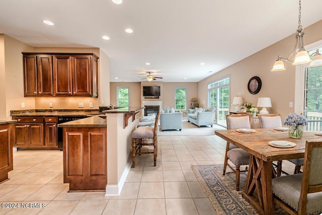 kitchen with light tile patterned floors, a glass covered fireplace, a breakfast bar area, a peninsula, and recessed lighting