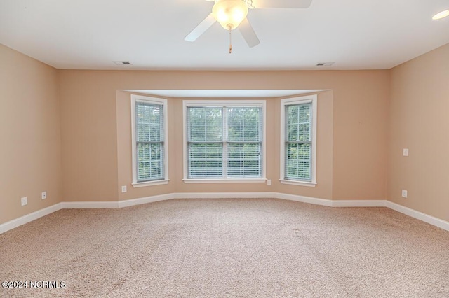 empty room featuring carpet floors, visible vents, ceiling fan, and baseboards