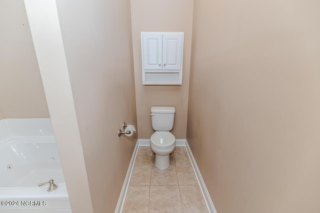 full bath featuring a jetted tub, baseboards, toilet, and tile patterned floors